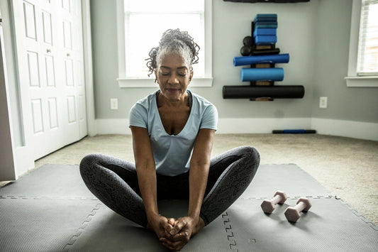 A woman working out and stretching on a light background in workout gear