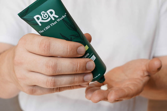 A man with a white shirt puts on R&R CBD Pain Cream