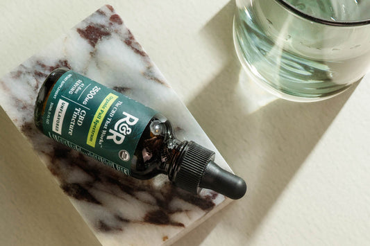 CBD Tincture on a marble block next to a glass of water